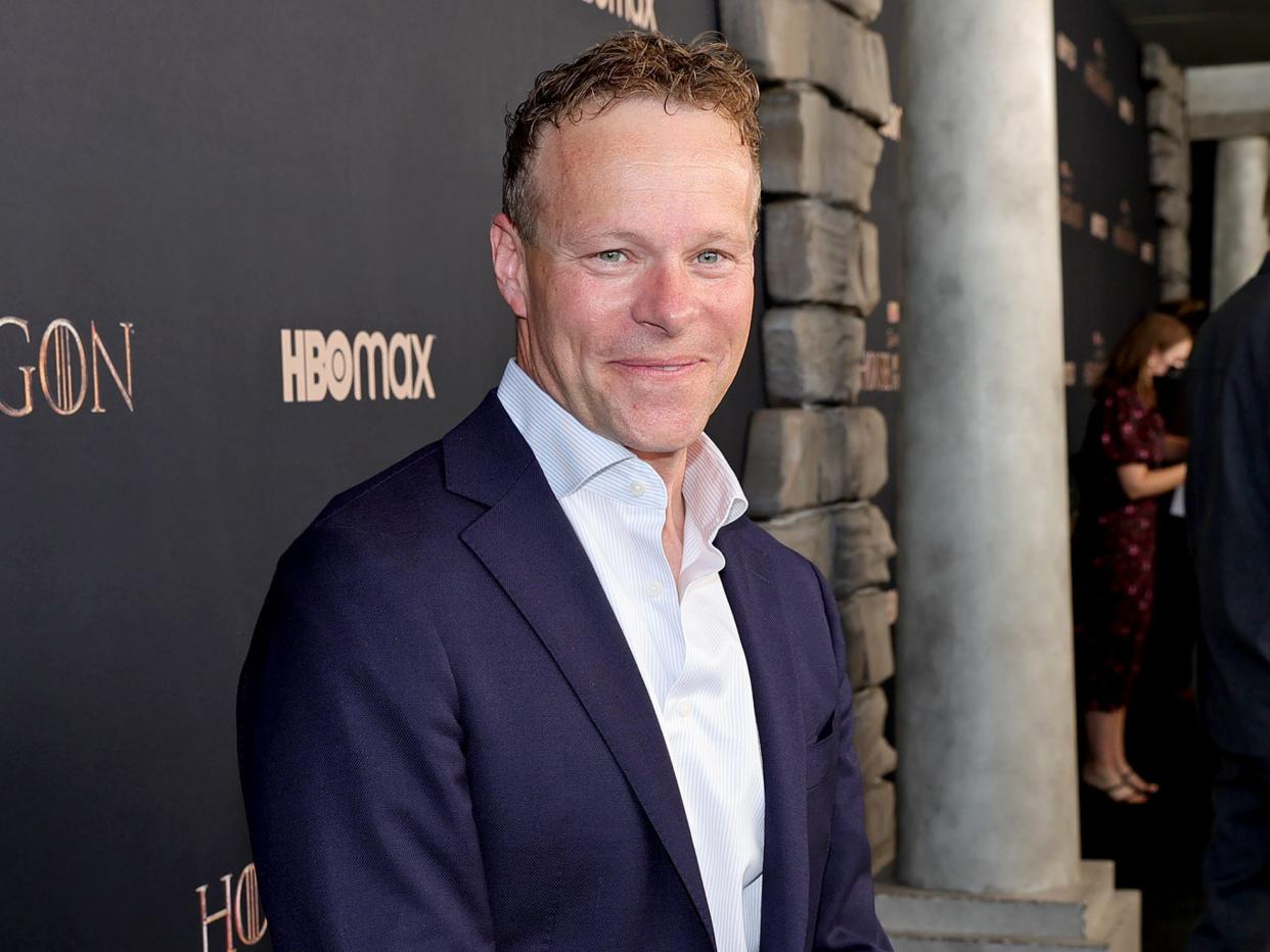 Chris Licht in a white shirt and blue blazer in front of an HBO backdrop with "House of the Dragon" on it.