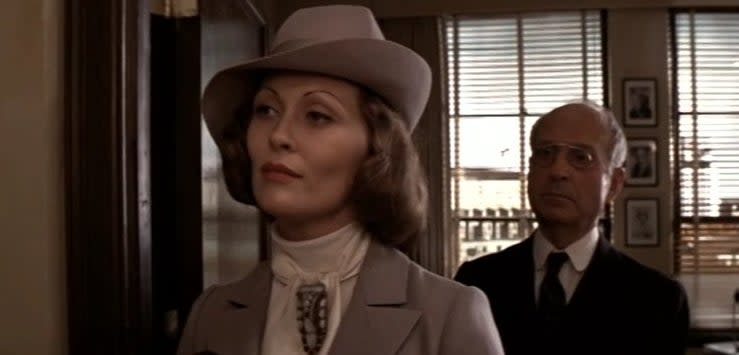 Evelyn standing in an office with a man behind her in "Chinatown"