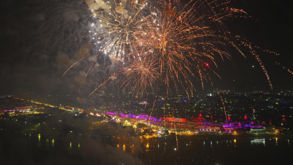 Fuegos artificiales iluminan el cielo mientras se encienden luces a orillas el río Saryu, la víspera del festival hindú de Diwali, en Ayodhya, India, el sábado 11 de noviembre de 2023. La ciudad de Ayodhya, en el estado norteño de Uttar Pradesh, la víspera de Diwali, lo que estableció un récord Guiness de número de lámparas encendidas, según la oficina de turismo del estado. (AP Foto/Rajesh Kumar Singh)