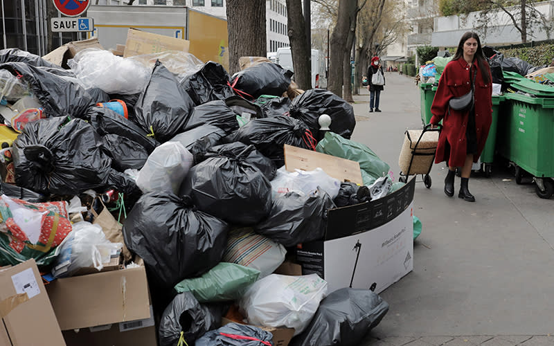 Paris residents walk past mounds of uncollected garbage in the streets