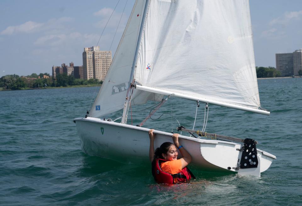 Lilly Bhogle, 14, of Canton, works to right the 420 sailboat she and her crewmate capsized while practicing on the Detroit River as they participate in the Challenge the Wind program on Thursday, July 20, 2023, from the banks of the Belle Isle Boat House.