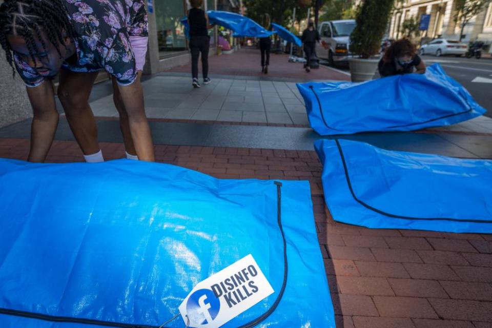 At Facebook’s Washington DC headquarters, activists lay body bags that read “disinfo kills”.