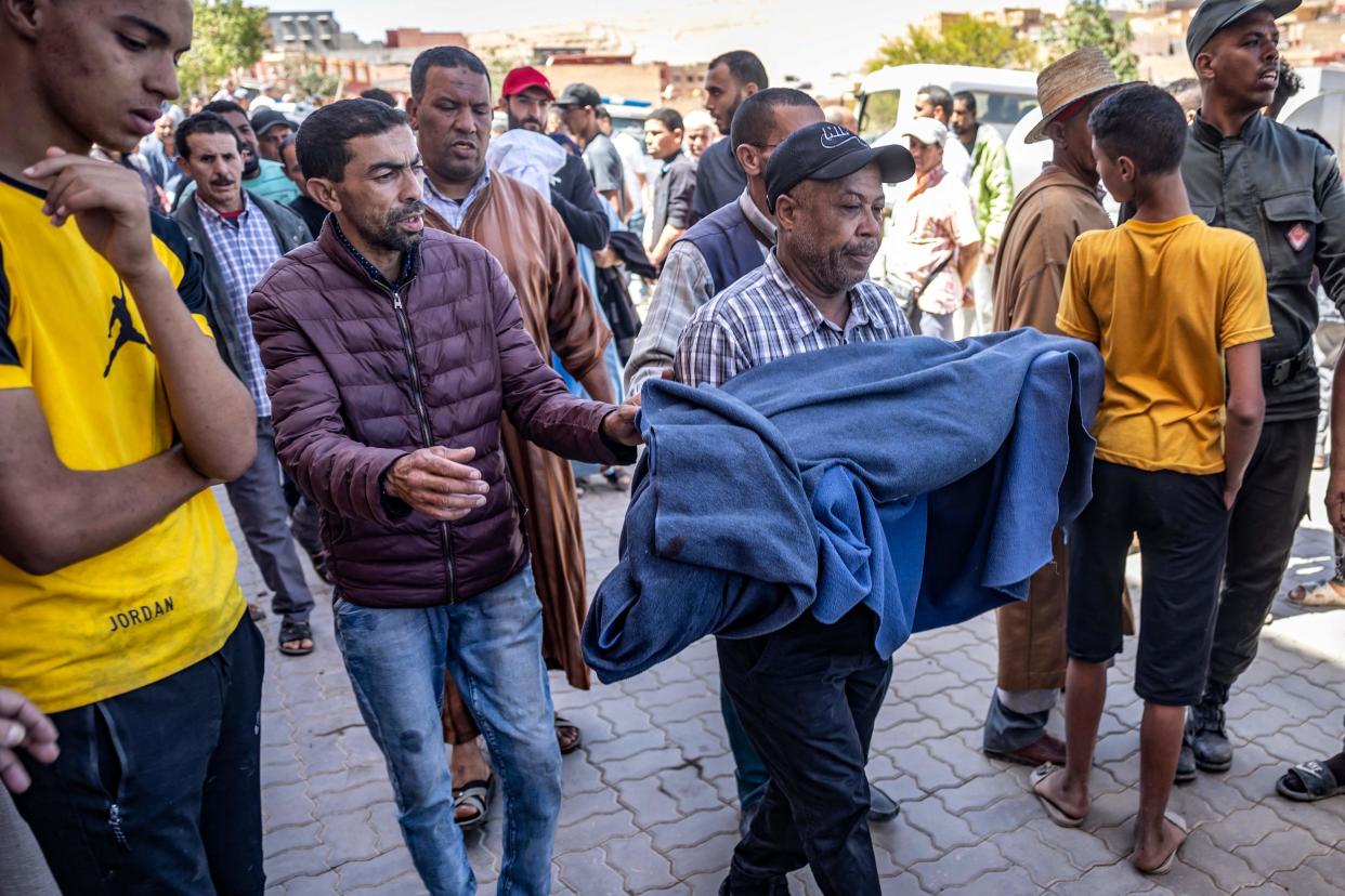 A man carries the blanket-wrapped body of a victim killed in an earthquake in Moulay Brahim, Al Haouz province (AFP via Getty Images)