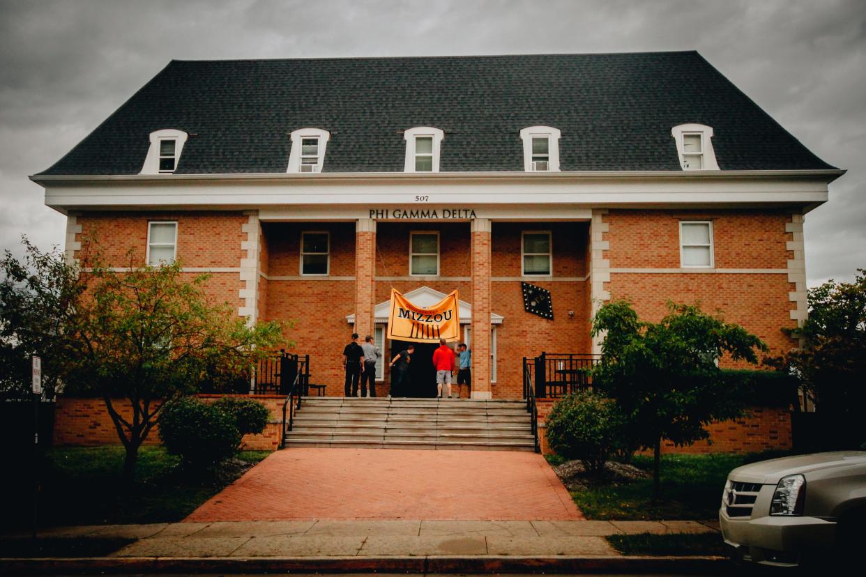 A University of Missouri banner is taken down as a storm rolls over the Phi Gamma Delta house during the fraternity's move-out day Oct. 24, 2021. Five days prior a fraternity pledge Danny Santulli was hazed, forced to drink a bottle of vodka, leading to alcohol poisoning and brain damage.