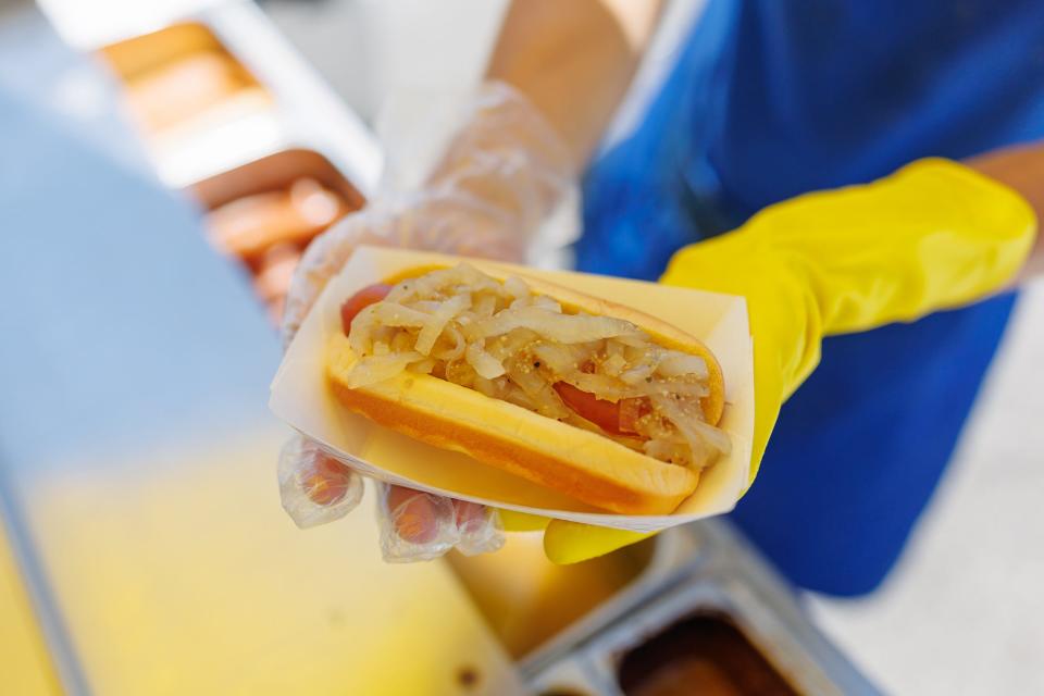 Connor Eisenhart, owner of The Homedog LLC, holds up one of his hotdogs from his hot dog cart in the parking lot of W.E. Sell Sporting Goods on the corner of Pleasant Street and York Street, Tuesday, May 21, 2024, in Hanover Borough.