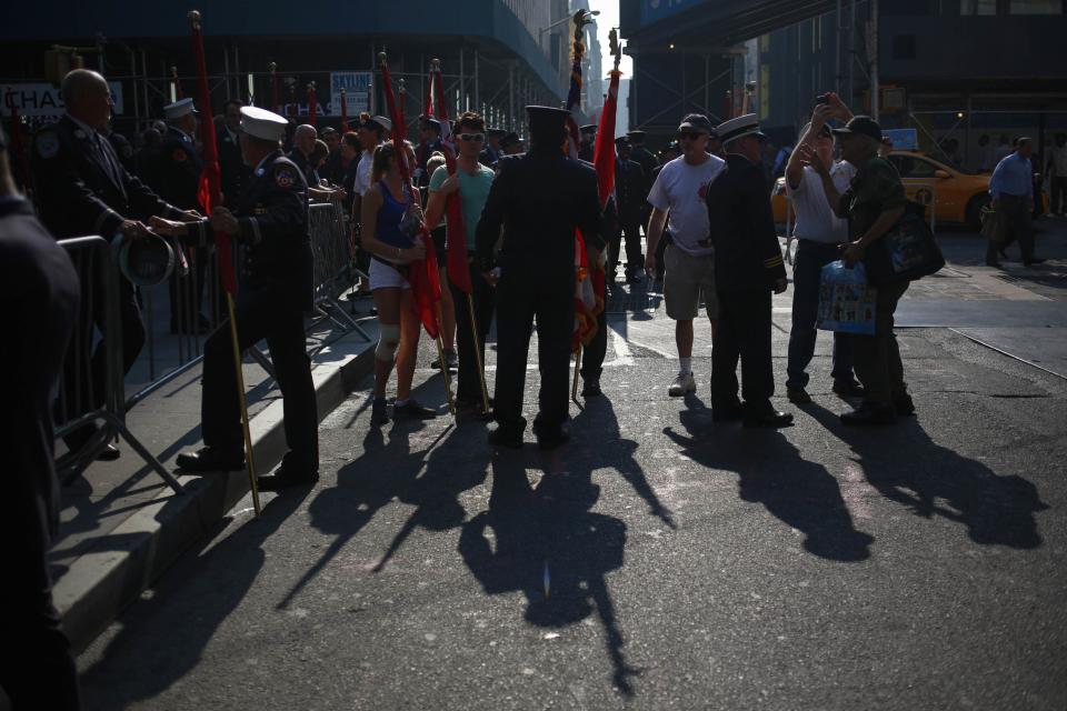 Members of the New York City Fire Department and others stand with flags after a moment of silence honoring the victims of the 9/11 attacks, outside the World Trade Center site in New York September 11, 2013. Bagpipes, bells and a reading of the names of the nearly 3,000 people killed when hijacked jetliners crashed into the World Trade Center, the Pentagon and a Pennsylvania field marked the 12th anniversary of the September 11 attacks in 2001. (REUTERS/Shannon Stapleton)