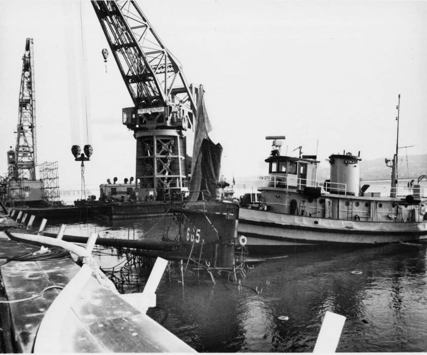 Guitarro after her sinking at Mare Island Naval Shipyard, Calif., showing medium harbor tug Satanta (YTM-270) positioned against the boat’s sail to prevent her from capsizing. (U.S. Navy Photo No. MSA 91770-5-69)