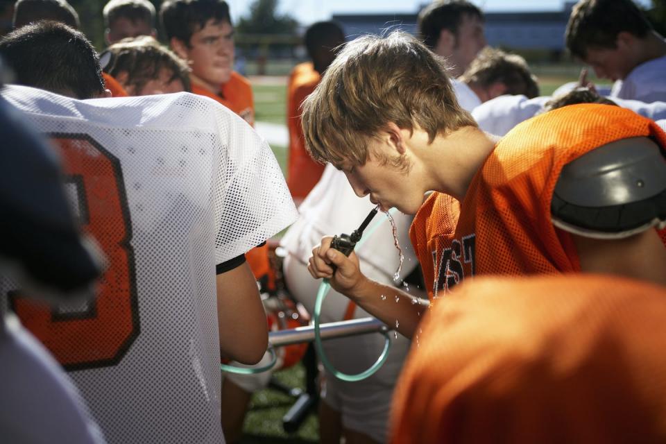 A young football player drinking water.