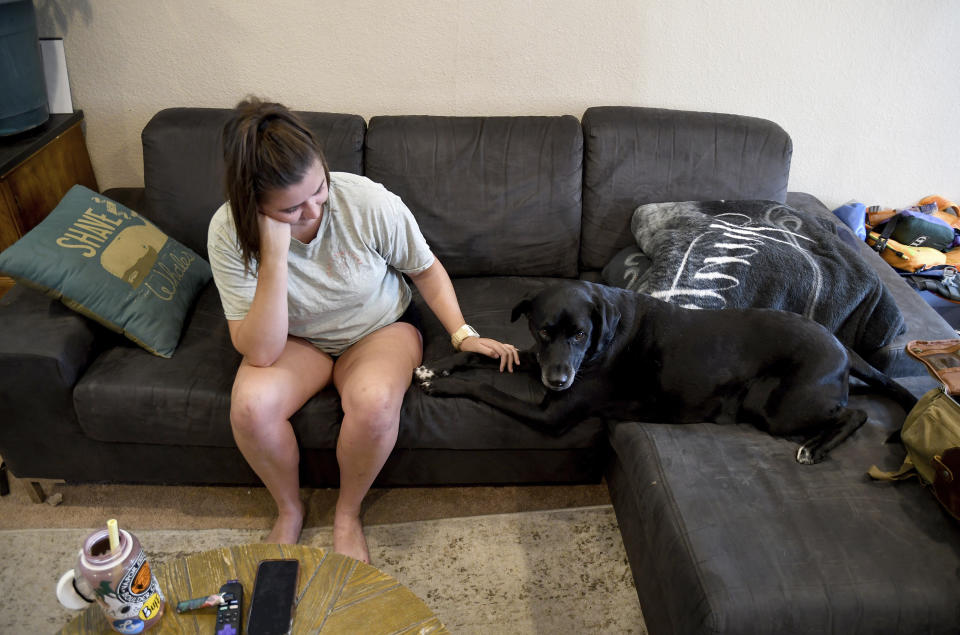 Gigi Kennedy pets her dog in her home in Denver's Globeville neighborhood on Monday, July 24, 2023. Kennedy said her landlord told her she could not set the air conditioning below 75 degrees Fahrenheit (23.8 Celsius). Her home consistently reaches temperatures in the 80s. America's poorest residents and people of color are far more likely to face grueling heat without air conditioning to keep their body temperatures down, according to a Boston University analysis of 115 U.S. cities. (AP Photo/Thomas Peipert)