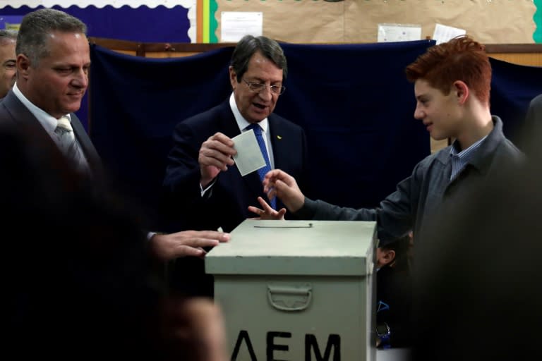 President Nicos Anastasiades casts his vote, accompanied by his grandchildren, at a polling station in the coastal city of Limassol on February 4, 2018 during the second round of the Cyprus presidential elections