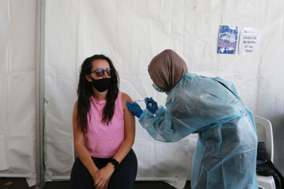 Enrolled Nurse Fatmar administers a Pfizer vaccination to a client attending the Belmore Sports Ground vaccination hub overseen by Dr. Jamal Rifi in Sydney, Australia. 