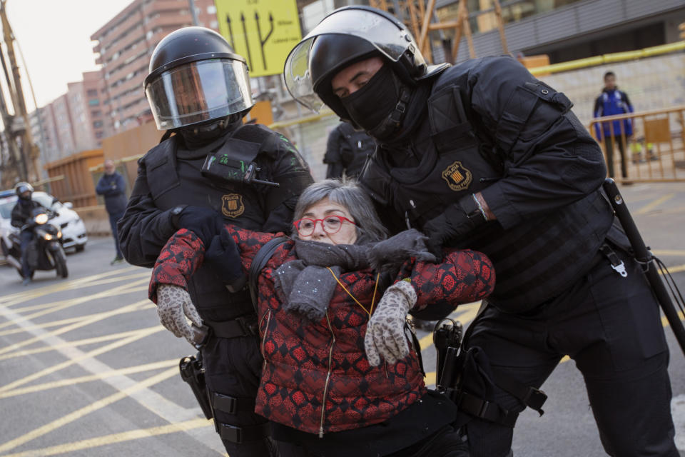 Catalan police officers remove a demonstrator blocking a road leading to Barcelona city, during a general strike in Catalonia, Spain, Thursday, Feb. 21, 2019. Strikers advocating for Catalonia's secession from Spain are blocking major highways, train lines and roads across the northeastern region. (AP Photo/Emilio Morenatti)