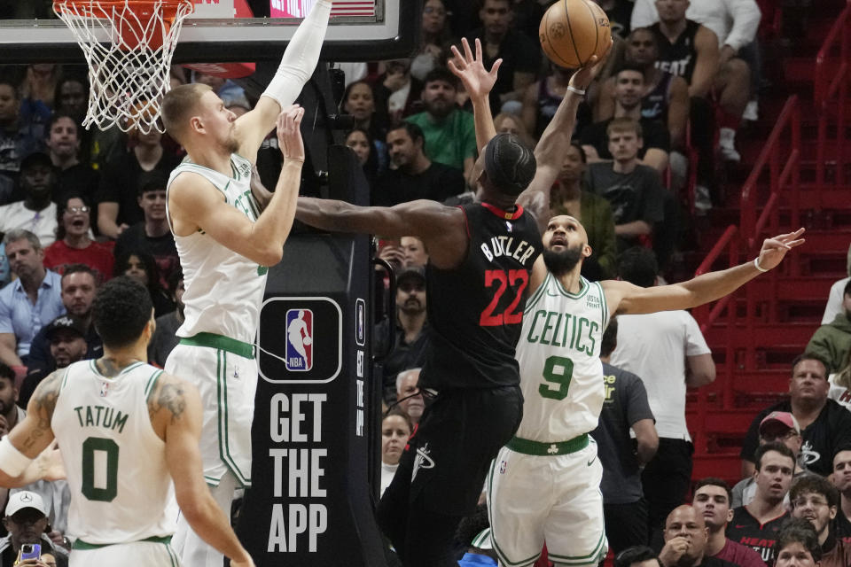 Boston Celtics guard Derrick White (9) and center Kristaps Porzingis (8) defend Miami Heat forward Jimmy Butler (22) during the first half of an NBA basketball game, Thursday, Jan. 25, 2024, in Miami. (AP Photo/Marta Lavandier)