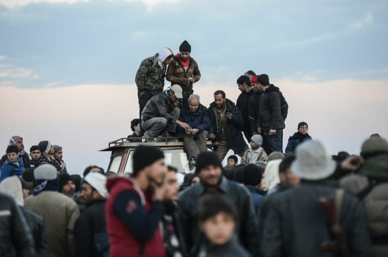 Men stand on a roof of a vehicle as Syrians fleeing the northern embattled city of Aleppo wait near a Turkish crossing gate on February 5, 2016