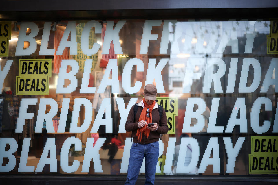 A person stands in front of Black Friday signage in shop windows during Black Friday on Oxford Street in London, Britain, November 25, 2022. REUTERS/Henry Nicholls