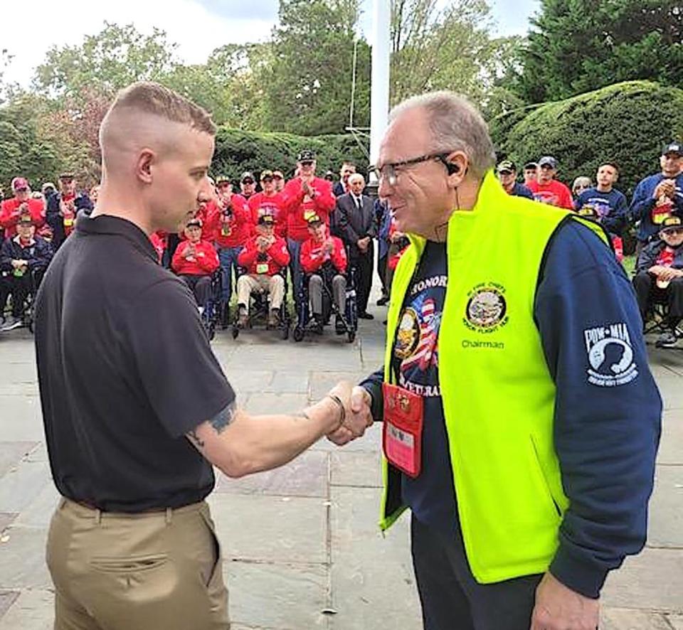 Chief George Farrell, right, chairman of the R.I. Honor Flight program, presents a Rhode Island Fire Chiefs Honor Flight challenge coin to one of the sentries at the Tomb of the Unknowns.