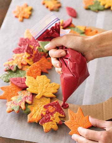 hands putting leaf cookies on a wreath base with frosting
