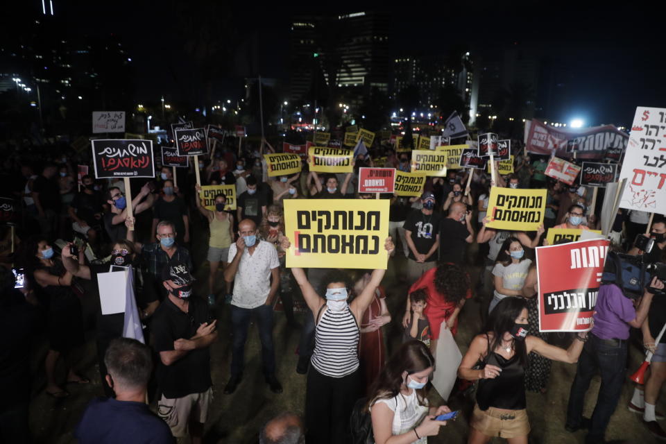 Israelis hold signs during a protest In Tel Aviv, Israel, Saturday, July 18, 2020. The sign says in Hebrew reads:"Out if touch, we are fed up." (AP Photo/Sebastian Scheiner)