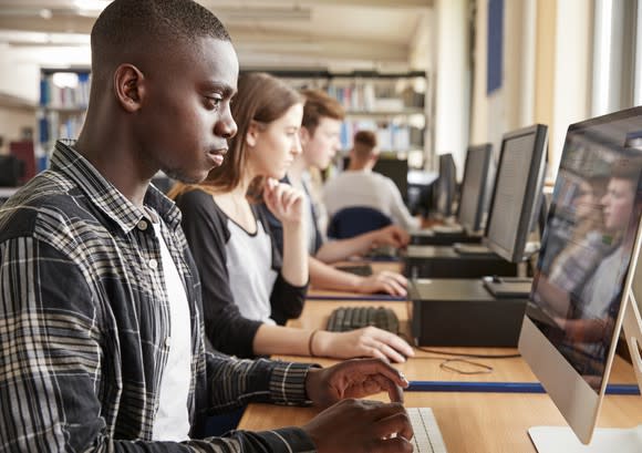 College-age people use computers in a library.