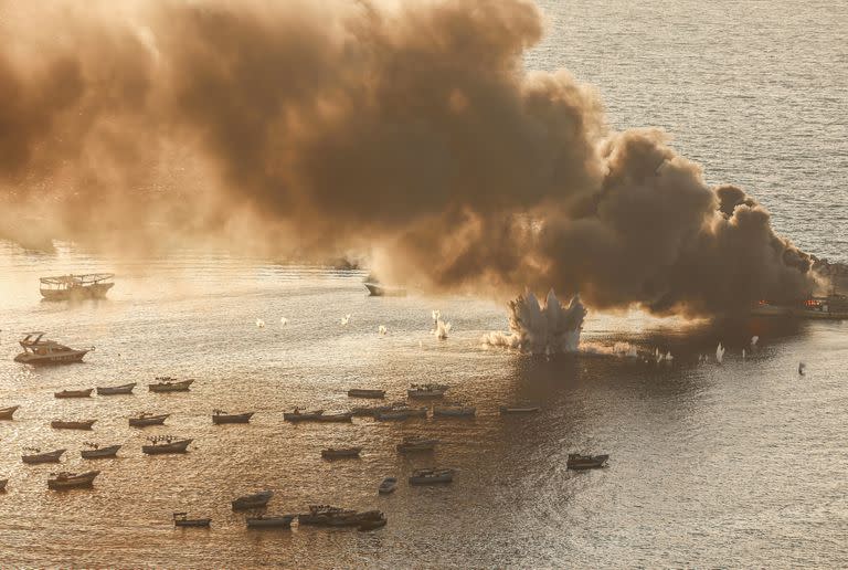 Fuego y humo se elevan tras los ataques israelíes contra un barco pesquero dentro del puerto marítimo de la ciudad de Gaza, mientras continúan los combates entre las fuerzas israelíes y el grupo militante palestino Hamas.