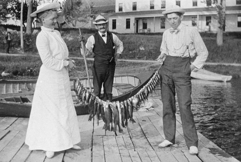 A man and woman display their fish catch, circa 1908.