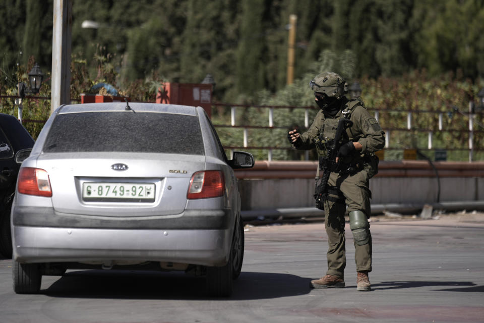 An Israeli soldier speaks to a motorist during a search in the West Bank village of Qafin for the suspected gunmen who shot and killed an Israeli civilian near the entrance to a Jewish settlement of Hermesh, Tuesday, May 30, 2023. (AP Photo/Majdi Mohammed)