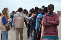 Illegal migrants stand next to members of the Red Crescent in the southeastern Tunisian port city of Zarzis on April 25, 2015, after they were rescued by fishermen when their boat got into difficulties while trying to sail from Libya to Europe