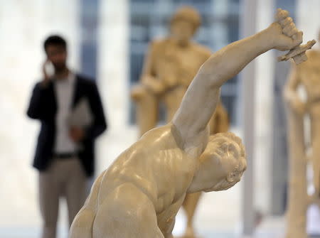 A man stands near a sculpture called "Torso of the Discobolus" at the Prada Foundation in Milan, May 6, 2015. Prada is launching a giant multi-disciplinary arts complex on the edge of Milan that it hopes will attract tens of thousands of visitors a year. REUTERS/Stefano Rellandini