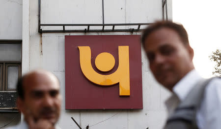 People stand in front of the logo of Punjab National Bank outside a branch of the bank in New Delhi, India February 15, 2018. REUTERS/Adnan Abidi