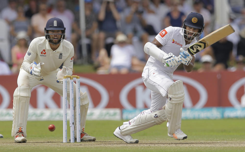 Sri Lanka's Dimuth Karunaratne plays a shot as England's Ben Foakes watches during the fourth day of the first test cricket match between Sri Lanka and England in Galle, Sri Lanka, Friday, Nov. 9, 2018. (AP Photo/Eranga Jayawardena)