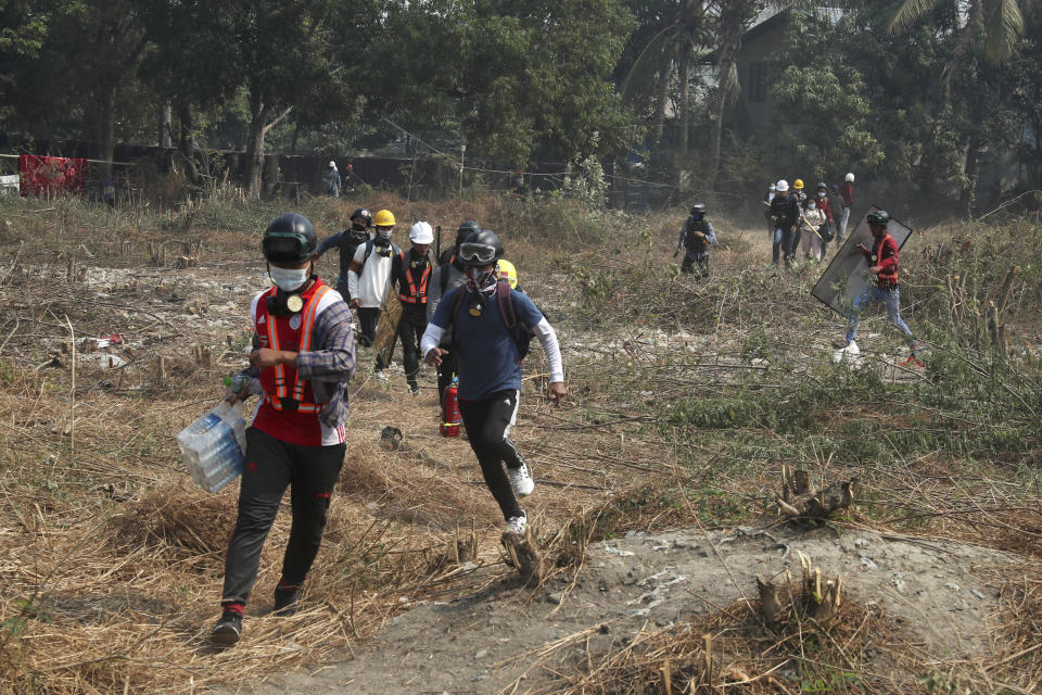 Anti-coup protesters run in an open field after police security forces try to disperse them with tear gas in Mandalay, Myanmar Saturday, March 13, 2021. Police in Myanmar fired rubber bullets and tear gas at protesters in the country's two largest cities and elsewhere on Friday, as authorities continued their harsh crackdown on opponents of last month's military coup. (AP Photo)