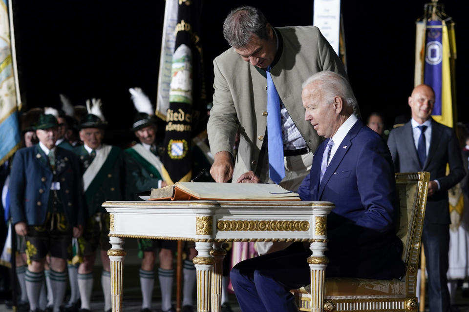 President Joe Biden signs the Golden Book of the Bavarian state government after arriving as Markus Soder, Minister-President of Bavaria, stands next to him at Munich International Airport in Munich, Germany, Saturday, June 25, 2022. Biden is in Germany to attend a Group of Seven summit of leaders of the world's major industrialized nations. (AP Photo/Susan Walsh)