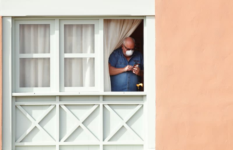 A guest, wearing a protective face mask, looks out from a window at H10 Costa Adeje Palace, which is on lockdown after cases of coronavirus have been detected there in Adeje