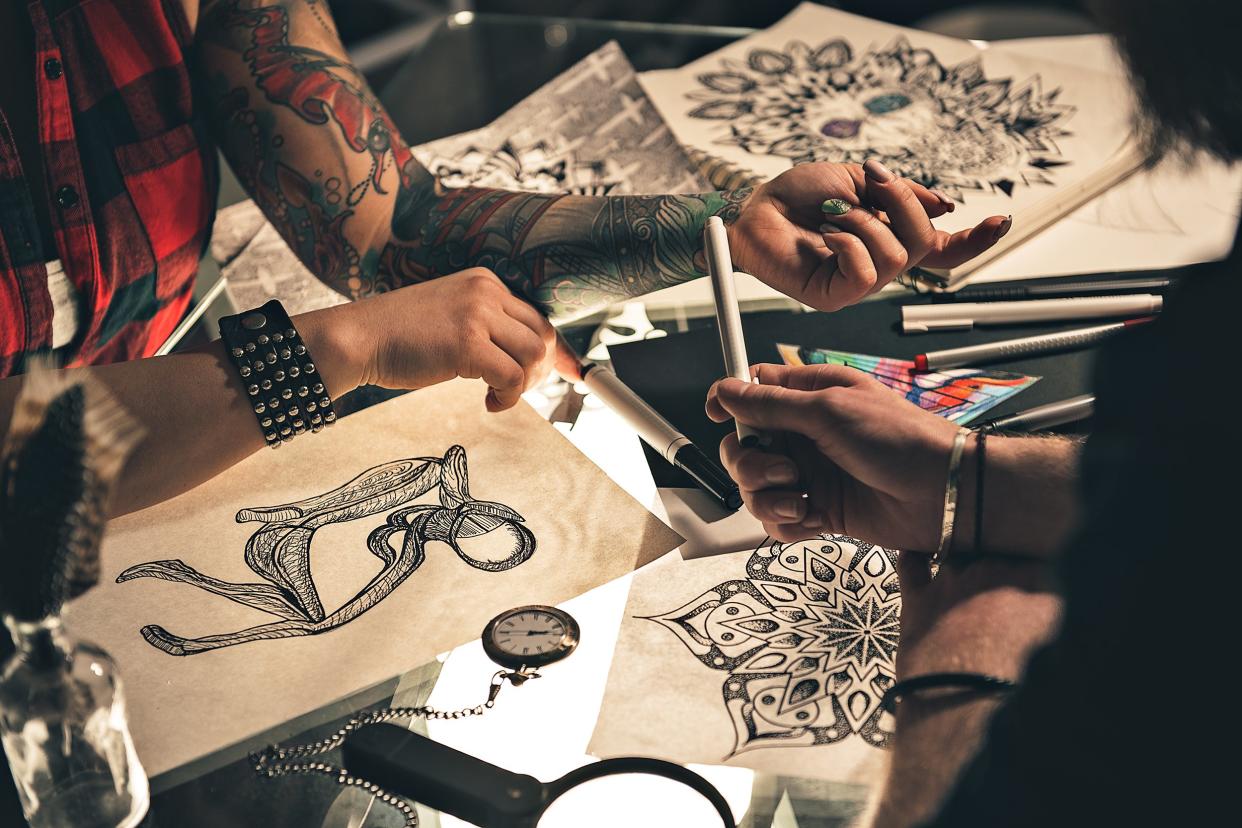two tattoo arts going over drawings