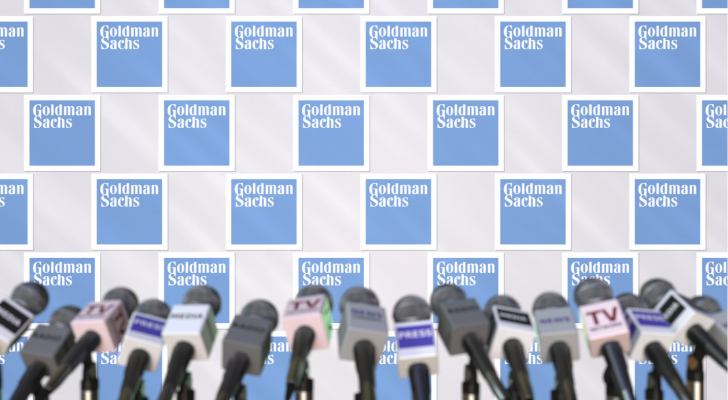 Goldman Sachs logo on light blue behind microphones. GS stock.