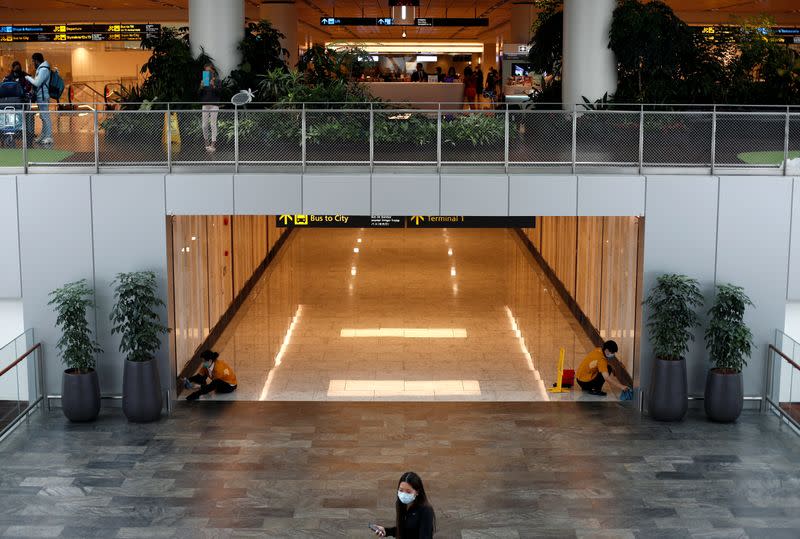 FILE PHOTO: Cleaners wearing masks in precaution of the coronavirus outbreak clean a corridor at Changi Airport in Singapore