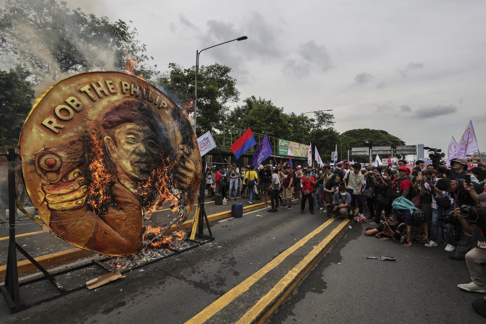 Protesters burn a two-faced gold coin effigy of President Ferdinand Marcos during a rally in Quezon City, Philippines, Monday, July 24, 2023, ahead of the second State of the Nation Address of Philippine President Ferdinand Marcos Jr. (AP Photo/Gerard Carreon)