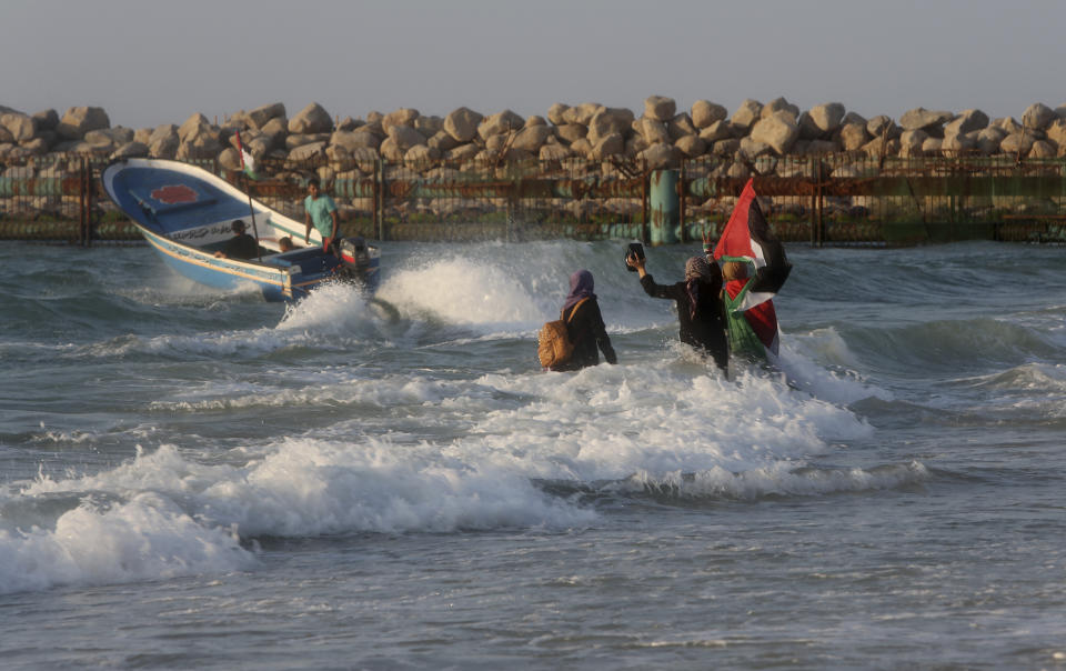 Palestinian women hold national flag during a protest on the beach at the border with Israel near Beit Lahiya, northern Gaza Strip, Monday, Sept. 17, 2018. (AP Photo/Adel Hana)