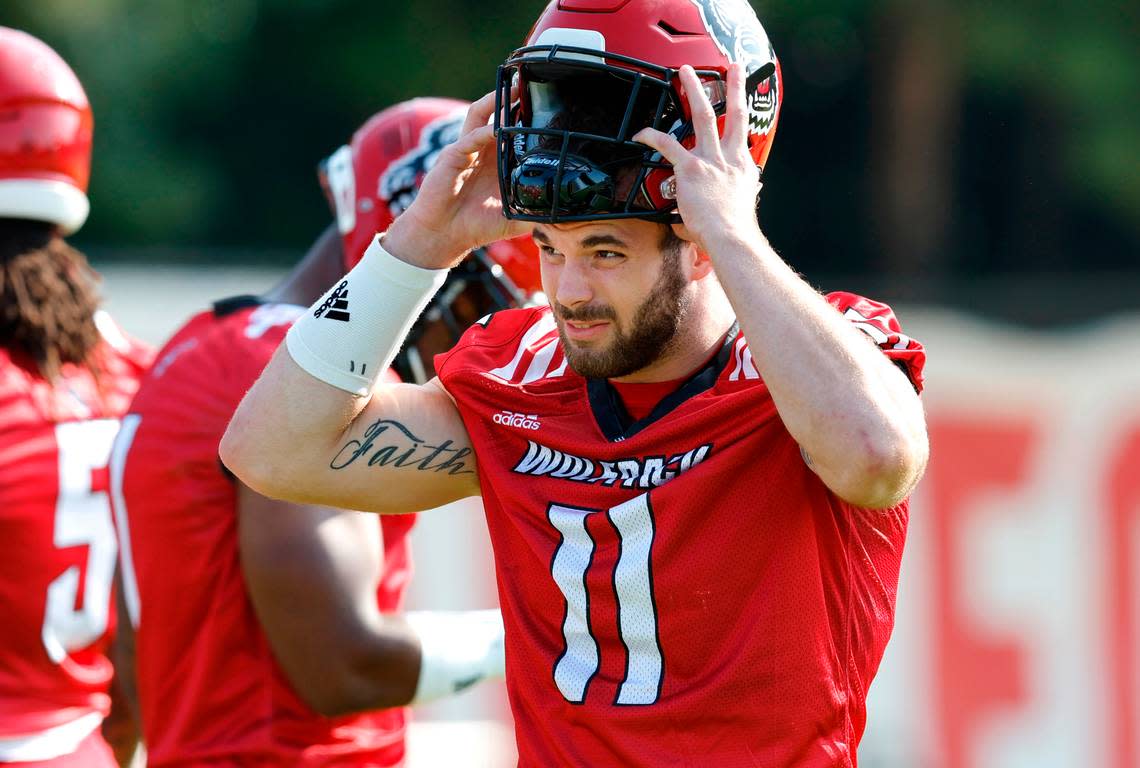 N.C. State linebacker Payton Wilson (11) puts on his helmet at the start of the Wolfpack’s first practice of fall camp in Raleigh, N.C., Wednesday, August 3, 2022.