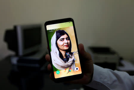 A man holds his mobile phone with a digital image of Nobel Peace Prize winner Malala Yousafzai at Khushal School in her home district in Swat Valley, Pakistan March 30, 2018. REUTERS/Faisal Mahmood