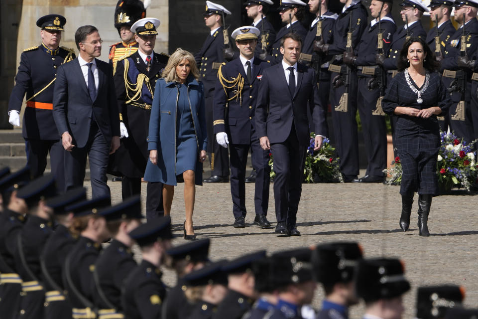 French President Emmanuel Macron, center right, his wife Brigitte Macron, Dutch Prime Minister Mark Rutte, left, and Amsterdam mayor Femke Halsema, right, arrive for a wreath laying ceremony in Amsterdam, Netherlands, Tuesday, April 11, 2023. French President Emmanuel Macron begins a two-day state visit to the Netherlands on Tuesday and is making a speech on his vision for the future of Europe. (AP Photo/Peter Dejong)