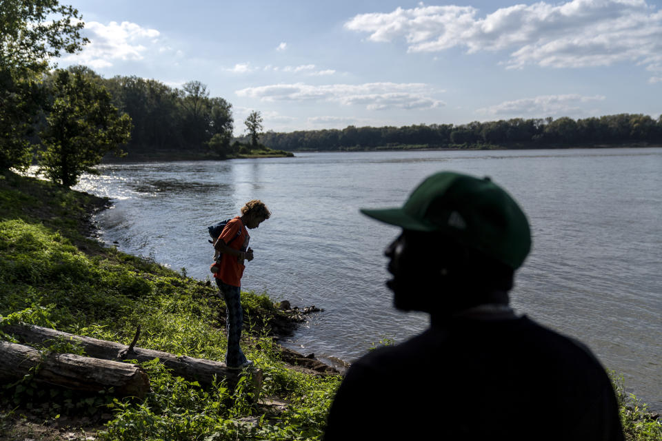 Navada Gwynn, right, visits the spot along the Ohio River where he used to fish with his son, Christian, in Louisville, Ky., Monday, Aug. 28, 2023, as his daughter, also named Navada, 15, stands at the water's edge. Christian, 19, was killed in a drive-by shooting four blocks from home in December 2019. Just two years later, Gwynn's older daughter, Victoria, then also 19, was shot and injured at a park on Louisville’s eastside. The 17-year-old friend she was there to meet was killed. (AP Photo/David Goldman)