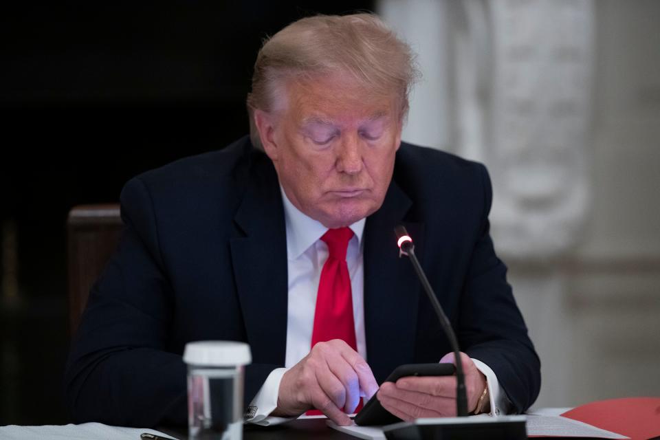 President Donald Trump looks at his phone during a roundtable with governors on the reopening of America's small businesses, in the State Dining Room of the White House on June 18, 2020.