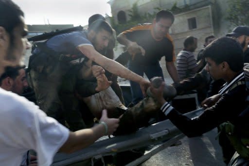 Syrian rebel fighters and locals help a man from a pick-up truck after he was wounded in shelling by government forces in Qusayr, southwest of Homs, in western Syria on Thursday