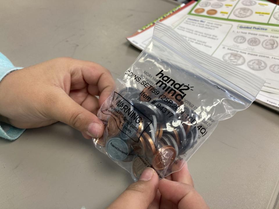 This Feb. 17, 2023 image shows a second-grade student holding play coins to her students in the Navajo community of To'Hajiilee, New Mexico. To'Hajiilee Community School is just one of dozens funded by the U.S. Bureau of Indian Education that are in desperate need of repair or replacement. The agency estimates it would cost roughly $6.2 billion to address the needs of those schools in poor condition. (AP Photo/Susan Montoya Bryan)