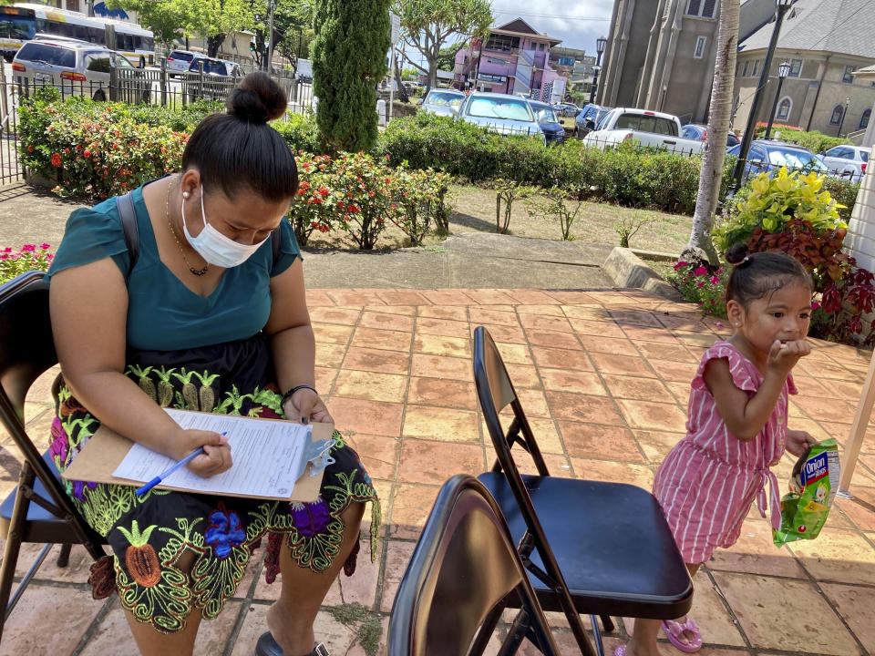 Shersina Roby fills out a form to get her second dose of the COVID-19 vaccine dose while 3-year-0ld Gezelle Fanny has a snack at a vaccination clinic in Honolulu, July 14, 2021. The pandemic has underscored the importance of collecting and reporting racial data. Honolulu City Councilwoman Esther Kiaʻāina says the pandemic's toll on Pacific Islanders who are not Native Hawaiian inspired her to introduce a resolution urging Hawaii government agencies to collect more specific data about Pacific Islanders. (AP Photo/Jennifer Since Kelleher)