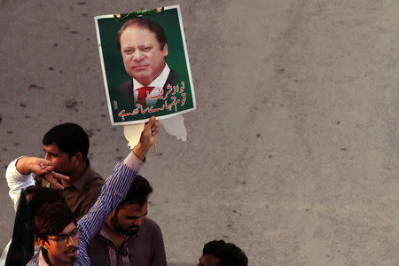 A supporter of the Pakistan Muslim League - Nawaz (PML-N) holds a portrait as he march towards the airport with others to welcome ousted Prime Minister Nawaz Sharif and his daughter Maryam, in Lahore, Pakistan July 13, 2018. REUTERS/Mohsin Raza