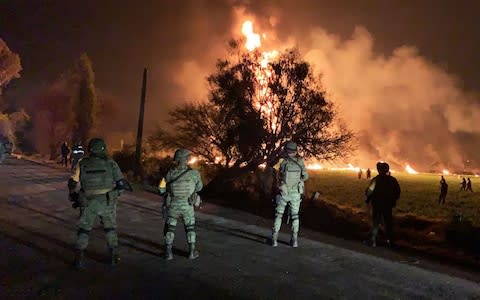 Mexican soldiers at a fire after a leaking gas pipeline triggered a blaze in Tlahuelilpan, Hidalgo state - Credit: AFP