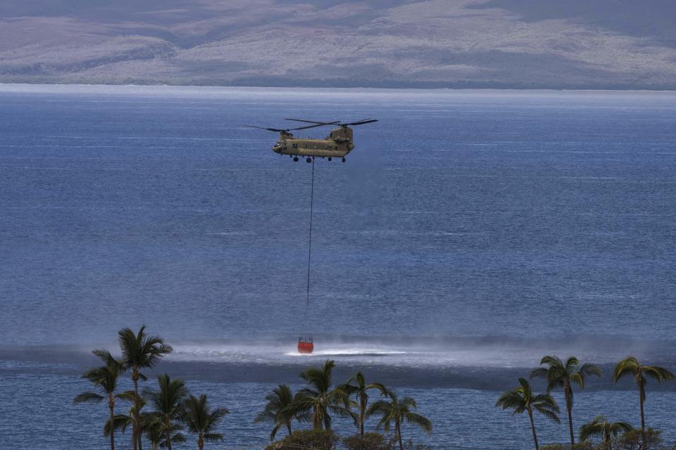 FILE - A Chinook helicopter scoops up water from the ocean near Lahaina, Hawaii, Aug. 16, 2023. Hawaii lawmakers on Wednesday, May 1, 2024, approved funds for more firefighting equipment and a state fire marshal after the deadliest U.S. wildfire in more than a century ripped through the historic Maui town of Lahaina and exposed shortcomings in the state's readiness for such flames. (AP Photo/Jae C. Hong, File)