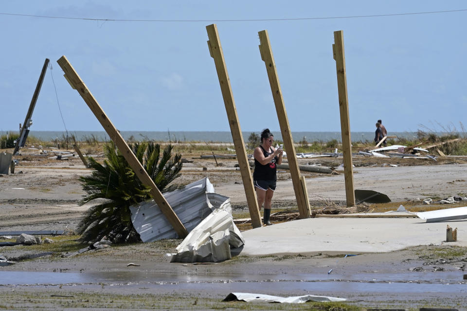 Pam Venissat, whose camp was destroyed by Hurricane Laura, takes a photo of the devastation in Holly Beach, La., Saturday, Aug. 29, 2020. (AP Photo/Gerald Herbert)